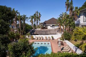 a swimming pool with lounge chairs and a house at Crawfords Beach Lodge in Chintsa