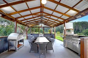 an outdoor kitchen with a table and chairs and a grill at Kin Kin Farm House - Pets Allowed in Kin Kin