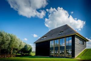 a black house with windows on a green lawn at Buitenplaats de Luwte in Zwolle