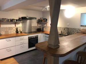 a kitchen with white cabinets and a wooden counter top at Le Refuge du Cap in Cescau