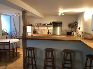 a kitchen with a bar with stools and a table at Le Refuge du Cap in Cescau