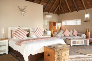 a bedroom with a large bed with pink and white pillows at Crawfords Beach Lodge in Chintsa +62 photos