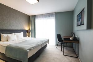 a bedroom with a bed and a desk and a window at Focus Hotel Poznań in Poznań
