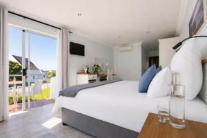 a bedroom with a large white bed and a balcony at BlueSky Arniston Boutique Guesthouse in Arniston +21 photos