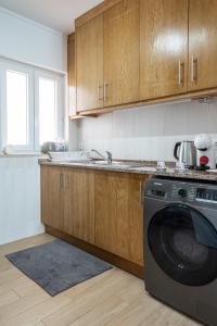 a kitchen with wooden cabinets and a washing machine at Na Casa da Fátima in Vila Nova de Milfontes