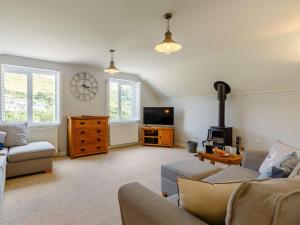 a living room with a couch and a clock on the wall at 4 Bed in Torpoint oc-89135 in Sheviock
