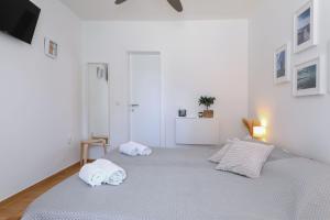 a white bedroom with two towels on a bed at Hibis, No 3 in Starigrad