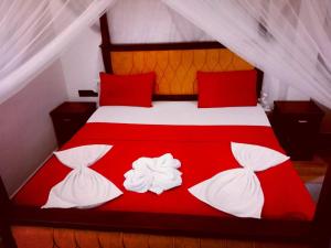 a red and white bed with four pillows on it at THARUMINI villa in Kandy
