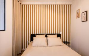 a bedroom with a bed with a striped wall at Le Choeur in Rodez