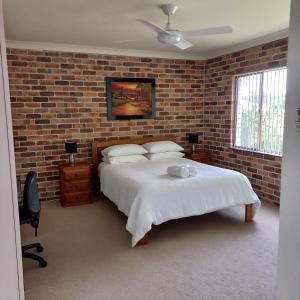 a bedroom with a bed and a brick wall at Emerald Tropical Palms B & B in Emerald Beach