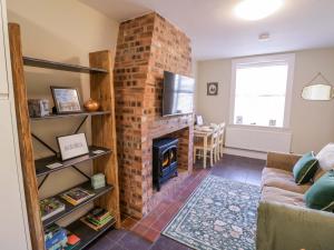 a living room with a brick fireplace with a tv at Fern Cottage in Lichfield