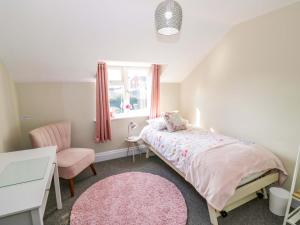 a bedroom with a bed and a chair and a window at Fern Cottage in Lichfield