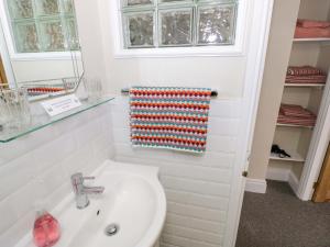 a white bathroom with a sink and a mirror at Fern Cottage in Lichfield +17 photos