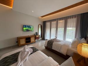 a bedroom with two beds and a tv on the wall at The Dura Ubud in Ubud