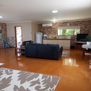 a living room with a black couch and a kitchen at Emerald Tropical Palms B & B in Emerald Beach