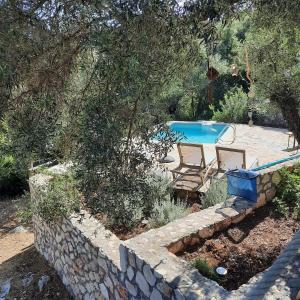 a backyard with a swimming pool and a stone wall at Mathilda's House in Tselendáta +18 photos