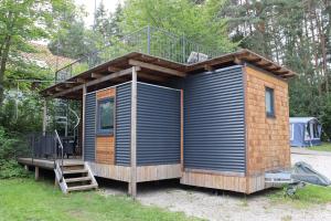 a tiny house with a deck and a staircase at NATURAMA Brombachsee Tinyhaushotel in Pleinfeld