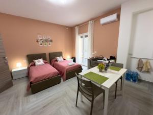 a room with two beds and a table and a dining room at Ferrera Suite & Rooms in Misterbianco