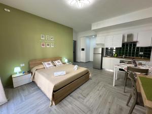 a bedroom with a large bed and a kitchen at Ferrera Suite & Rooms in Misterbianco