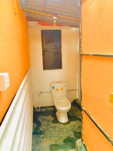 a small bathroom with a toilet in an orange room at Blue Vibe in Arugam Bay +41 photos