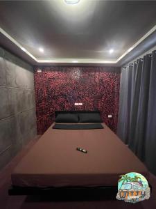 a bed in a room with a red wall at Witty Woods Guesthouse in Camalig