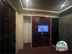 a room with a wall with a tv on it at Witty Woods Guesthouse in Camalig