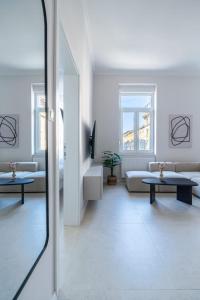 a white living room with two tables and a couch at Palmotić Heritage Suites - Main Square - FREE Parking in Zagreb