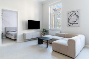 a white living room with a couch and a tv at Palmotić Heritage Suites - Main Square - FREE Parking in Zagreb