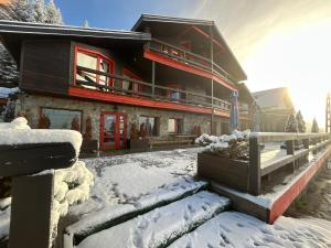 a large house with a red door in the snow at Pensiunea Alpin SPA in Ranca