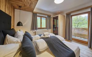 a hotel room with two beds and a window at Chalet Wallehen by we rent, JOKERCARD INCLUDED in Saalbach-Hinterglemm