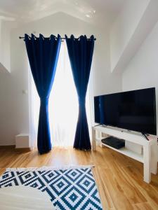 ein Wohnzimmer mit Fernseher und blauem Vorhang in der Unterkunft Villa Blanca - Risan in Risan