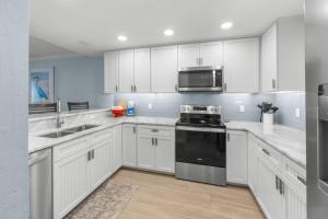 a kitchen with white cabinets and a stove top oven at Sunset Captiva Bayside Unit 103 condo in Captiva