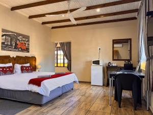 a bedroom with a bed and a desk and a kitchen at Hendersons Lodge Ltd in Senekal