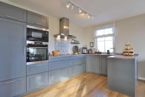 a large kitchen with blue cabinets and a counter at Das Reethaus in Groß Schwansee
