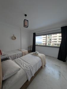 a bedroom with two beds and a large window at Tanger City 2 in Tangier +14 photos
