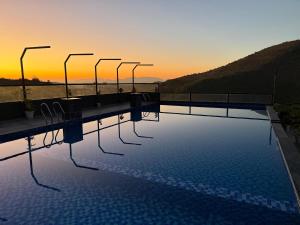 a swimming pool with a sunset in the background at The Divine Hills Resort Suites with Private Pool Near IIM Udaipur in Nāi