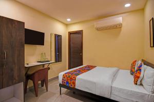 a bedroom with a bed and a desk with a computer at FabHotel The Crown Aura in kolkata
