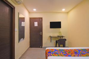 a room with a bed and a table and a television at FabHotel The Crown Aura in kolkata