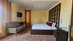 a hotel room with a bed and a chair at Grand Mumtaz Tangmarg in Tangmarg