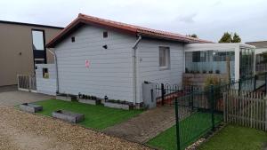 a white house with a fence in a yard at Maas Chalet Aldeneik in Maaseik