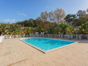 a large swimming pool in a yard with palm trees at Résidence LA CROISIERE in Anglet