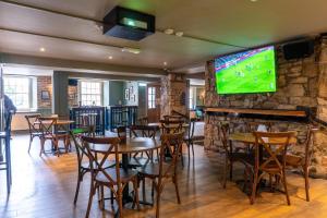a restaurant with tables and a tv on a stone wall at Tyacks Hotel in Camborne