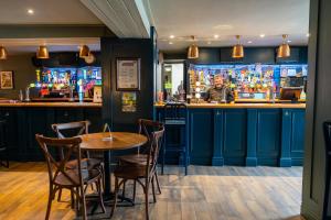 a bar with blue cabinets and a table and chairs at Tyacks Hotel in Camborne