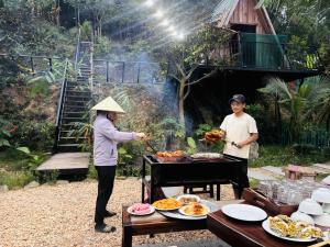 a woman and a man preparing food on a grill at Bird House Ecolodge Nghệ An in Hữu Biêt