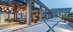 an outdoor patio with tables and chairs and lights at Kempinski Hotel Muscat in Muscat