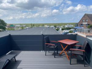 a table and chairs on a balcony with a parking lot at Meerzeit Strandhotel in Neuharlingersiel
