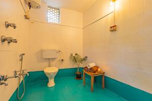 a bathroom with a toilet and a table with a plant at The Yellow House By Leela in Patnem