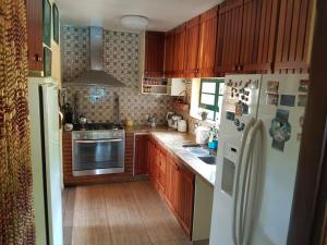 cocina con armarios de madera y nevera blanca en Casa Com Piscina, en Campinas