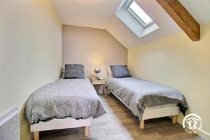 two beds in a bedroom with a skylight at Du bonheur à la campagne in Mauron