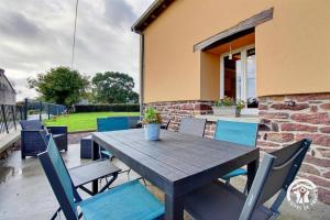 a wooden table and chairs on a patio at Du bonheur à la campagne in Mauron